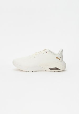Chaussure de sport blanche Puma avec semelle rembourrée et logo Puma doré sur le côté du talon, vue de côté gauche sur fond blanc.