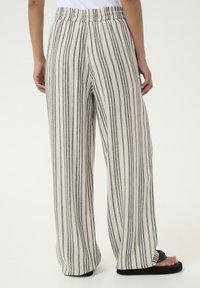 Pantalons à jambes larges avec une base crème et des rayures verticales grises, une taille élastique et une texture de tissu légère.