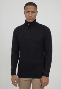 Marineblauer Strickpullover mit hohem Kragen und halbem Reißverschluss, ausgestattet mit gerippten Bündchen und Saum. Strukturierter Stoff mit klassischer Passform.
