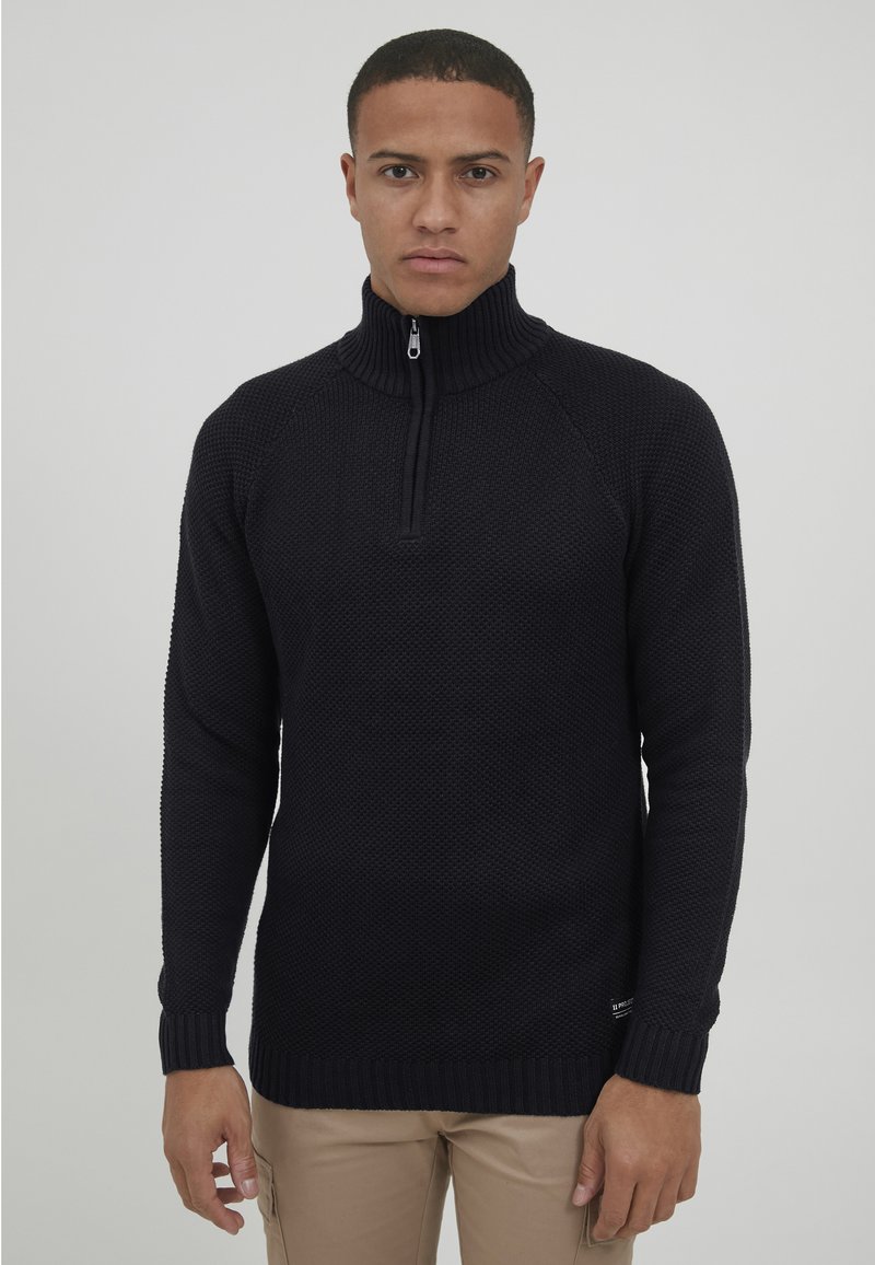 Marineblauer Strickpullover mit hohem Kragen und halbem Reißverschluss, ausgestattet mit gerippten Bündchen und Saum. Strukturierter Stoff mit klassischer Passform.