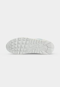 Λευκή σόλα παπουτσιού Nike με υφή και μοτίβα κράτησης και το λογότυπο Nike που είναι ανάγλυφο στο κέντρο σε απλό λευκό φόντο.