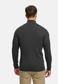 Tmavě šedý svetr s copánkovým vzorem, vysokým límcem a žebrovanými manžetami, se strukturovaným vzorem a přiléhavým střihem.