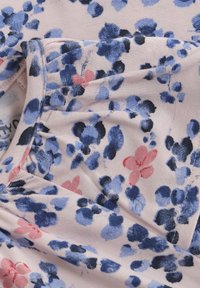 Blommönstrad tyg med nyanser av blått, rosa och svart på en ljusrosa bakgrund. Mjuk textur och r gathered detaljer.