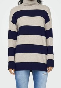 Gestreifter Rollkragenpullover mit abwechselnden beigen und marineblauen Streifen, gerippten Bündchen und lockerer Passform, kombiniert mit hellblauen Jeans.