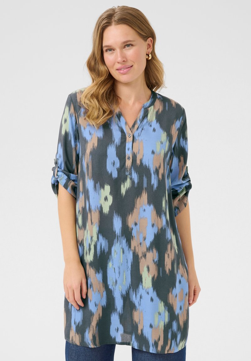 Knopen-tunic van lichtgewicht, gemusterd stof in tinten blauw, groen en bruin, met opgerolde mouwen en een V-hals ontwerp.