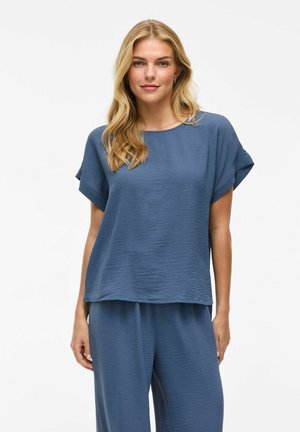 Haut à manches courtes, à coupe décontractée en tissu bleu texturé, avec un col rond et un design ample, associé à un pantalon assorti.