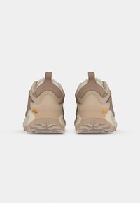 Brune og beige sneakers med en struktureret overdel, robust ydersål og en løftestrop bagpå, designet til komfort og støtte.