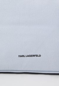 Pochette en tissu texturé bleu clair avec un logo noir "KARL LAGERFELD". Finition lisse avec des bords nets et un design minimaliste.