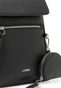 Mochila de cuero negro texturizado con un bolsillo frontal con cremallera y un monedero redondo acoplado, con herrajes plateados y un logotipo.