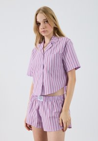 Ensemble de pyjama à manches courtes rayé en violet clair avec des rayures verticales rose foncé ; comprend une chemise à boutons et un short à taille élastique.