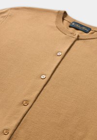 Sweter kardigan w kolorze wielbłądzim, z okrągłym dekoltem i zapinany z przodu na guziki, posiadający cztery guziki oraz prążkowany kołnierz.