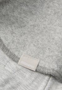 Gray felt fabric with a smooth texture, featuring a stitched neckline and a label with "maximo" in white.