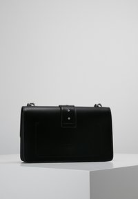 Borsa a mano in pelle nera con un design strutturato, caratterizzata da una patta prominente, hardware in argento e dettagli di cucitura sottili.