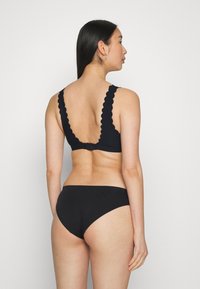 Conjunto de sutiã e cueca preto com bordas rendadas e um design de costa baixa. Textura suave com um estilo minimalista. Alças ajustáveis.