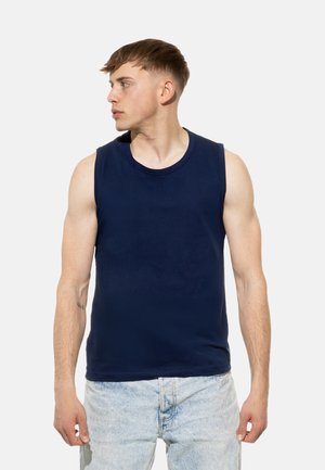 Maglietta senza maniche blu navy in tessuto morbido con scollo rotondo, abbinata a pantaloni corti in denim blu chiaro. Modello di profilo.