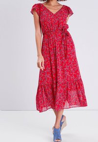 Robe rouge à fleurs, longueur genou, avec décolleté en V, manches volants, taille élastique et lien sur le côté, présentant une jupe fluide et un ourlet à volants.
