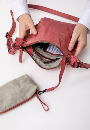 Rote Leder-Crossbody-Tasche mit strukturierter Oberfläche, ausgestattet mit einem Reißverschluss und gefüttertem gestreiften Innenleben. Enthält ein passendes Federmäppchen.