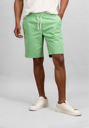 Groene katoenmix korte broek met een elastische tailleband en witte trekkoord, voorzien van zijzakken en een losse pasvorm. Gematched met witte sneakers.