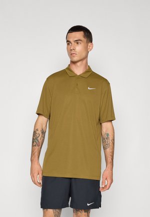 Olivgrünes Poloshirt mit kurzen Ärmeln und Kragen; mit einem weißen Nike-Logo auf der linken Brust, kombiniert mit dunklen Sportshorts.