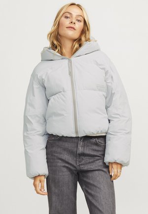 Lichtgrijze pufferjack met capuchon, vooraan een rits en elastische manchetten. Beschikt over een gladde textuur en minimale branding op de borst.