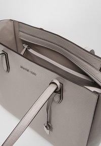 Borsa tote in pelle grigia con design strutturato, dotata di manici doppi, tasca interna con cerniera e finitura testurizzata. Logo impresso sul davanti.