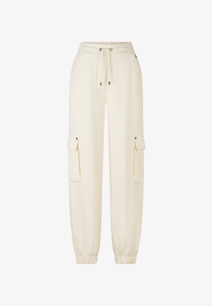 Kremowe spodnie dresowe z elastycznym pasem, sznurkiem, mankietami u kostek i dwoma bocznymi kieszeniami cargo z zatrzaskami. Gładka tekstura.