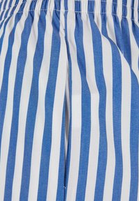 Tissu rayé verticalement bleu et blanc avec une taille élastique froncée, probablement une partie d'un vêtement tel que des shorts ou un pantalon.