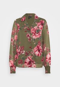 Blusa floreale con uno sfondo verde oliva, grandi fiori rosa e rossi, maniche lunghe e colletto con chiusura a bottoni.