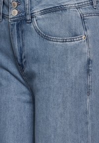 Vaaleansiniset farkut, joissa on kaksinappinen suljenta, etutasku ja hieman haalistunut pinta. Klassinen suora lahje, jossa on hienovaraiset tikkaus yksityiskohdat.