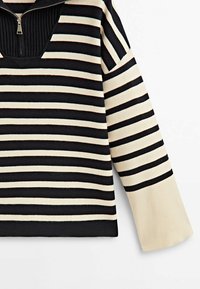 Pull-over rayé bleu marine et crème, avec un col à demi-fermeture éclair, une texture côtelée et des manches larges avec des poignets contrastants.