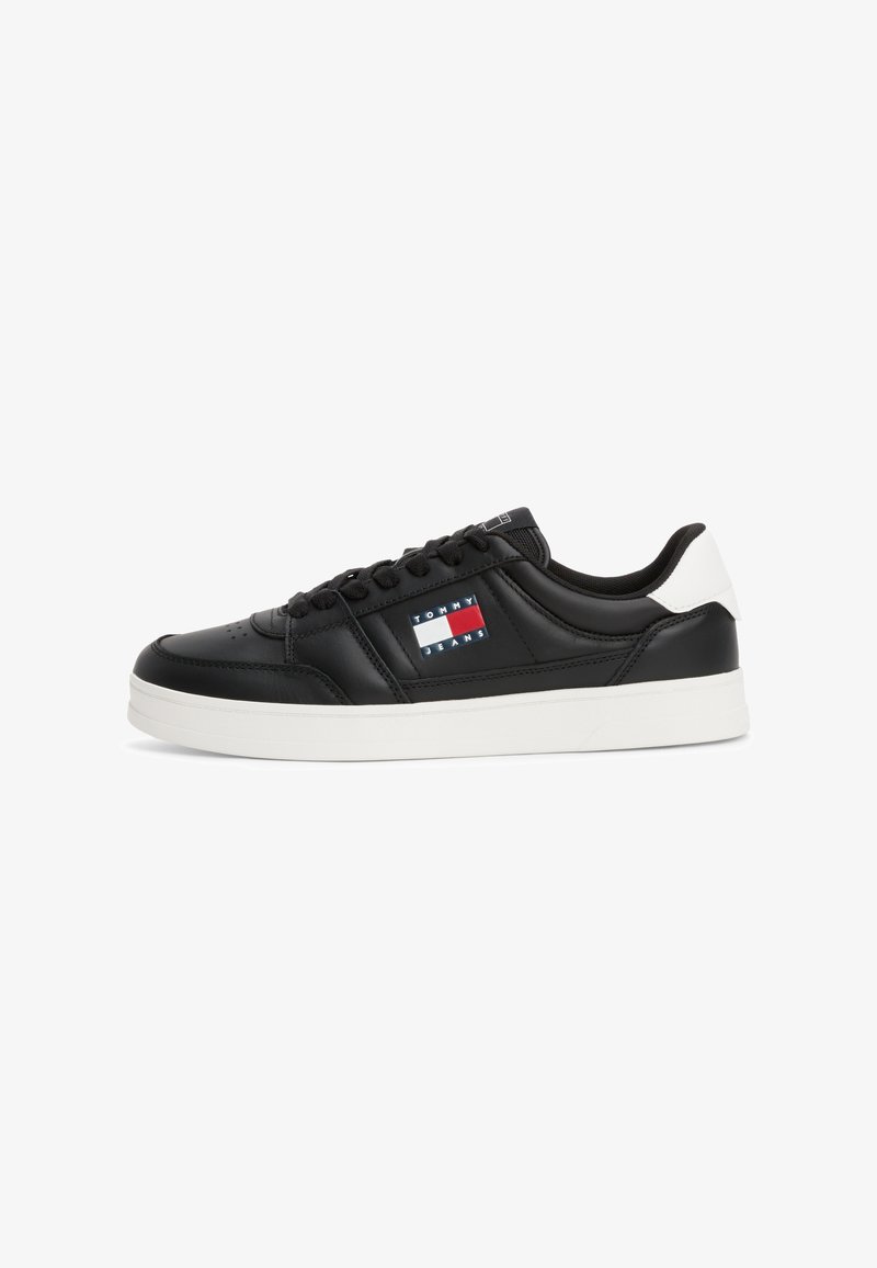 Baskets basses noires avec semelle blanche et patch au talon, comportant le logo Tommy Jeans en rouge, blanc et bleu sur le panneau latéral.