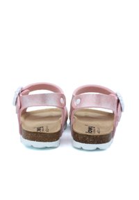 Sandale rose avec accents métalliques, sangle réglable, semelle en liège et semelle en caoutchouc blanc. Décorée d'un motif floral sur la sangle.