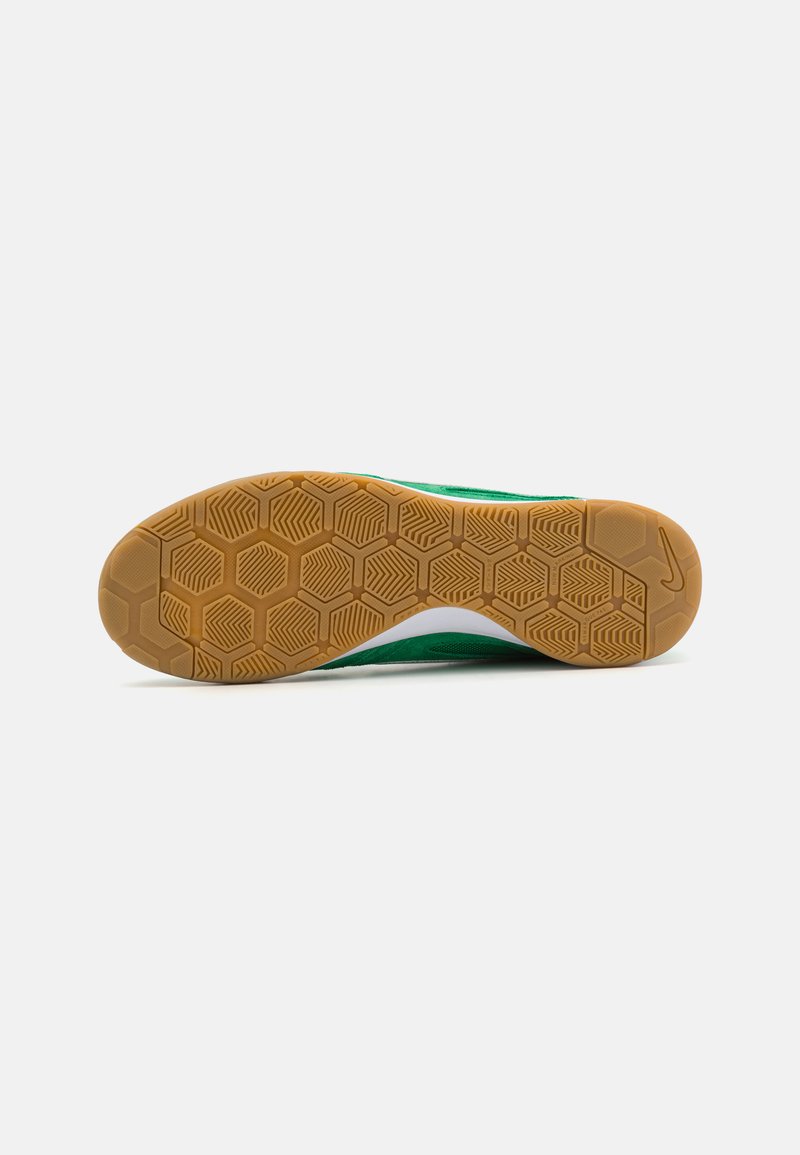 Suela de zapatilla verde con una suela de goma texturizada que presenta un patrón de panal, destacada por una entresuela blanca y acentos adicionales.