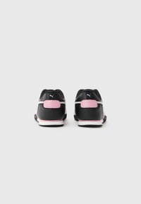 Et par svarte og hvite Puma-sneakers med rosa hælaksenter vist fra baksiden på en enkel hvit bakgrunn.