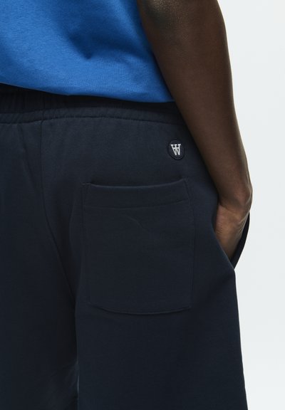 Shorts en coton bleu marine avec taille élastique, dotés d'une poche arrière et d'un patch logo avec un accent blanc "W". Texture lisse.
