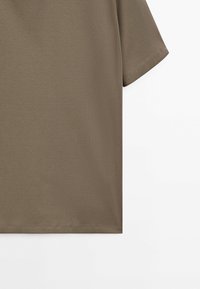 Short-sleeve plain olive green t-shirt shown against a white background, focusing on the lower half of the body and sleeve.