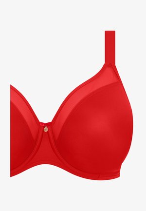 Červená podprsenka s hladkými košíčky a průhlednými krajkovými detaily, s nastavitelnými ramínky a malým dekorativním kovovým doplňkem uprostřed.