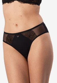 Czarne majtki bikini z przezroczystymi panelami siateczkowymi, haftem kwiatowym w ciemnych odcieniach oraz małym metalowym akcentem w kształcie pierścionka z przodu.
