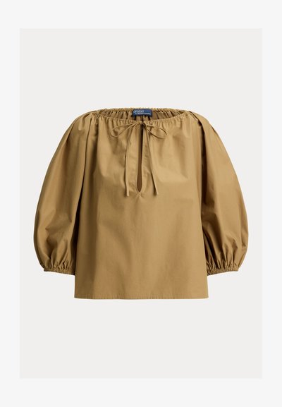 Καφέ βαμβακερό μπλουζάκι με στρογγυλεμένο λαιμόκοψη, μανίκια φουσκωτά και κορδόνι στον λαιμό. Ομαλή υφή και άνετη εφαρμογή.