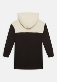 Mikina s kapucí, která má béžovou horní část a černou dolní část, vyrobená z měkkého materiálu s žebrovanými manžetami a lemováním.