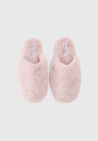 Pantufas felpudas cor-de-rosa com parte de trás aberta, apresentando laços decorativos de contas. Textura suave e forma arredondada para conforto. Etiqueta da marca visível.