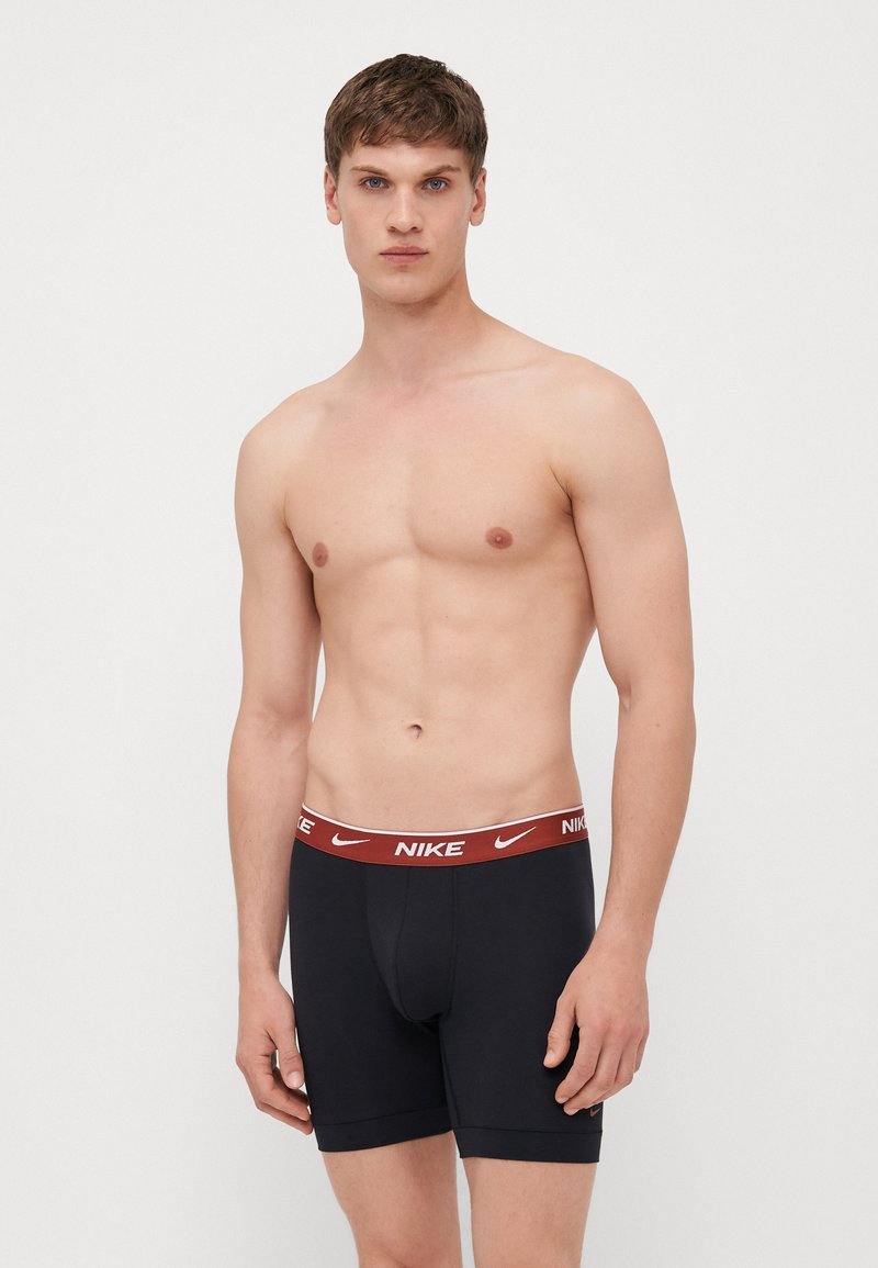 Boxers en coton noirs de Nike avec une ceinture rouge arborant le logo de la marque, tissu lisse, design ajusté et longueur mi-cuisse.