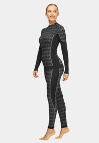Czarny zestaw sportowy z wzorzystą bluzą z długim rękawem i dopasowanymi legginsami, z kontrastującymi panelami bocznymi i wysokim kołnierzem.