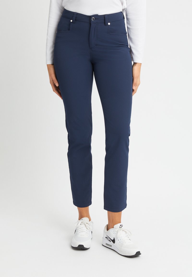 Navy blue stretch pants with a slim fit, featuring two front pockets, a button closure, and cuffed hems. Paired with white sneakers.