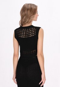 Crop top nero in maglia con design testurizzato, maniche corte e un motivo a rete aperta lungo la schiena e i fianchi.