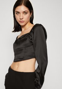 Crni satenasti crop top s kvadratnim izrezom, dugim naboranim rukavima i glatkom teksturom, s uskim krojem.