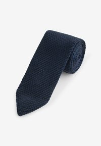 Corbata de punto en azul marino con una superficie texturizada, diseño estrecho, punta puntiaguda y forma enrollada, que presenta una estructura de tejido abierto y transpirable.