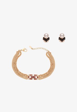 Bransoletka z łańcuszka w złotym odcieniu z zapięciem wysadzanym czerwonymi kamieniami szlachetnymi, w komplecie z kolczykami wkrętami z pereł z czarnymi prostokątnymi akcentami.