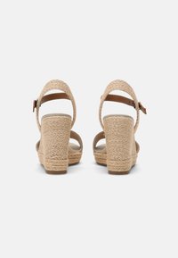 Beige kilehæle sandaler med flettet jute-detalje, justerbar ankelrem og åben hæl. Tekstureret sål for bedre greb.