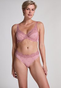 Ensemble de lingerie en dentelle rose comprenant un soutien-gorge et une culotte assortie. Le soutien-gorge présente des broderies florales et des bonnets rembourrés, tandis que la culotte a une ceinture en dentelle à bords festonnés.